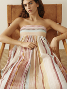 Model sitting in pastel striped long dress